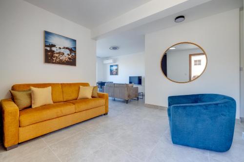 a living room with a yellow couch and a mirror at Valley's Edge Apartments in San Ġwann