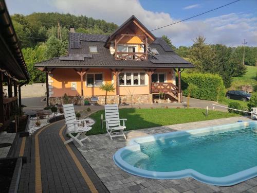 a house with a swimming pool in front of a house at Jaśkowa Chata Bieszczady apartament z basenem in Baligród