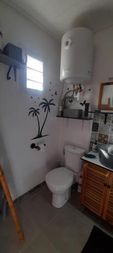 a bathroom with a toilet with palm trees on the wall at Le LiloVert - Studio 24 m2 in Le Carbet
