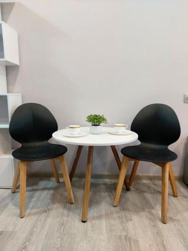 einem Tisch mit zwei schwarzen Stühlen und einem weißen Tisch mit zwei Stühlen in der Unterkunft Светлые апартаменты- Афины in Almaty