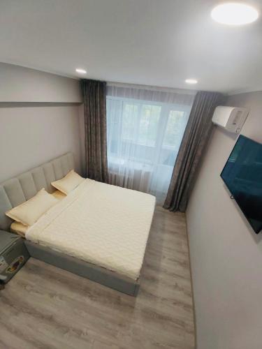 a bedroom with a bed and a flat screen tv at Светлые апартаменты- Афины in Almaty
