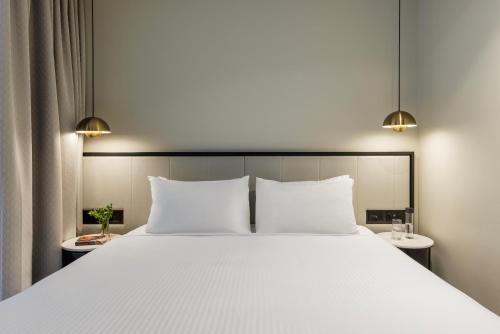 a bedroom with a large white bed with two tables at Brady Hotels Jones Lane in Melbourne