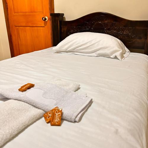 a bed with white towels and a pillow at Casa Hotel Los Fundadores in La Victoria
