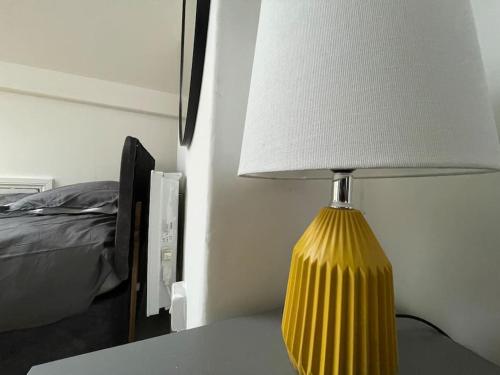 a yellow lamp sitting on a table next to a bed at 1 Bedroom flat with En-suite in Belle Isle