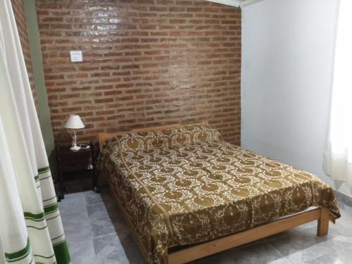 Ce lit se trouve dans une chambre dotée d'un mur en briques. dans l'établissement Casa quinta vuelta de obligado, à Vuelta de Obligado