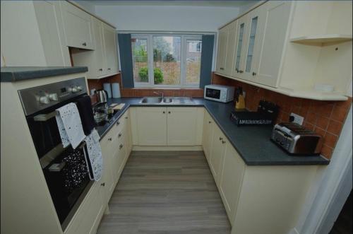 a kitchen with white cabinets and black counter tops at Charming 5 Bedroom House in Bexley in Bexley