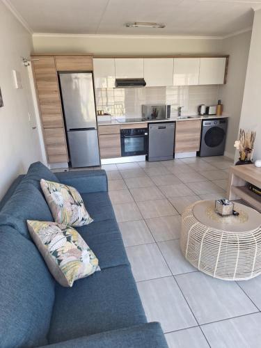 a living room with a blue couch and a kitchen at Prunell in midrand in Midrand