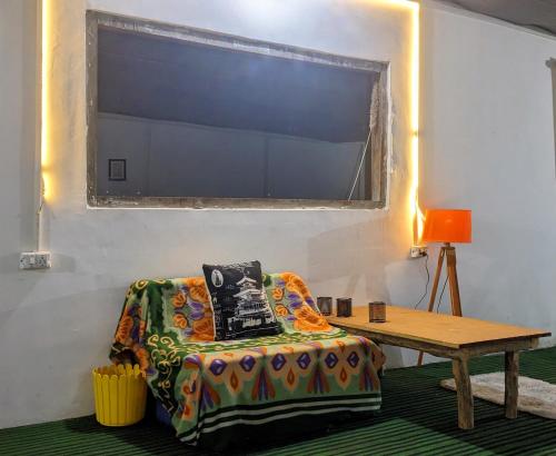 um quarto com um sofá, uma mesa e uma janela em Damnbro Cafe & Stay KASOL em Kasol