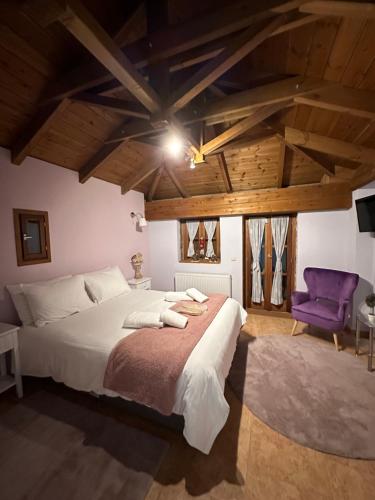 a bedroom with a large bed and a purple chair at Country Stone House ,next to Kalavrita in Kalavrita