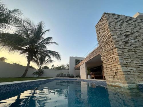 una piscina junto a un edificio con una palmera en La Villa Samba Ngaparou, en Ngaparou