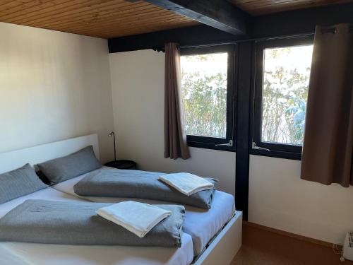 two beds in a room with two windows at Bungalow Nordschwarzwald im Ferienpark Schellbronn in Neuhausen