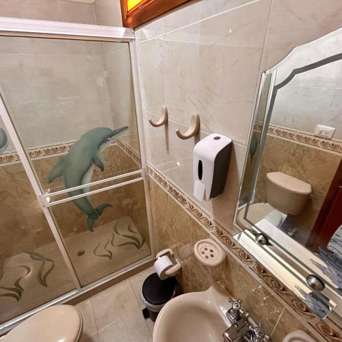 a bathroom with a dolphin in the shower at Casa Hotel Los Fundadores in La Victoria