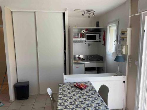 a small kitchen with a table and a refrigerator at Maison avec terrasse et jardin à 600m de la plage in Berck-sur-Mer