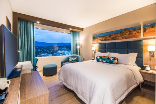 una camera d'albergo con un letto e una grande finestra di Hampton By Hilton Cucuta a Cúcuta