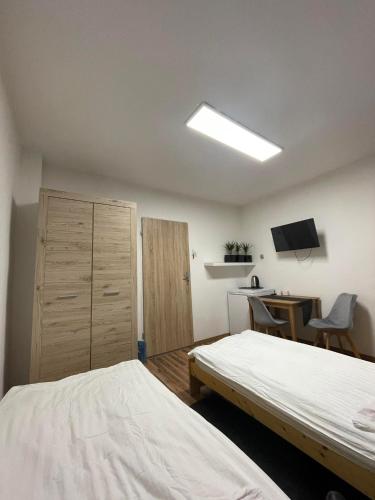 a bedroom with two beds and a desk and a television at Hostel BYTOMSKA in Września