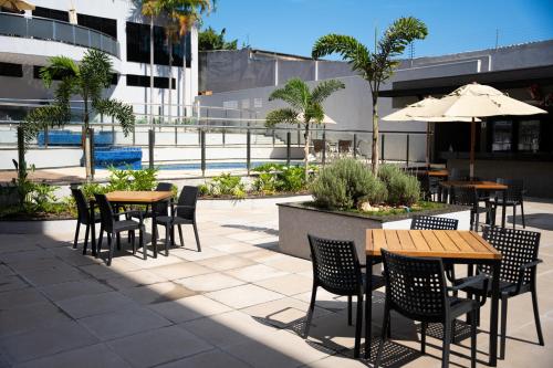 un patio con mesas, sillas y una sombrilla en Foz Plaza Hotel, en Foz do Iguaçu