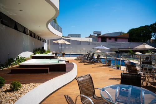 a patio with chairs and tables and a swimming pool at Foz Plaza Hotel in Foz do Iguaçu