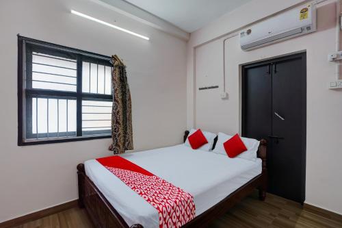 Un dormitorio con una cama con almohadas rojas y una ventana en OYO Flagship Hotel I stayz, en Madurai