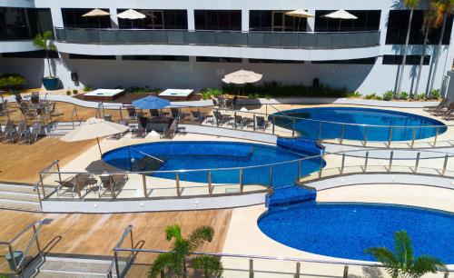 uma piscina do hotel com duas piscinas e mesas e guarda-sóis em Foz Plaza Hotel em Foz do Iguaçu