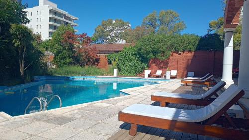 una piscina con bancos junto a un edificio en Bagu Pinamar Hotel en Pinamar