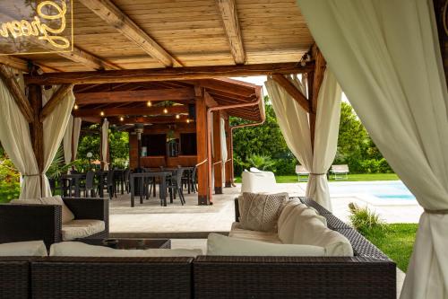 eine überdachte Terrasse mit Sofas, einem Tisch und Stühlen in der Unterkunft Green Oasis Gabella Monolocale in Castelforte