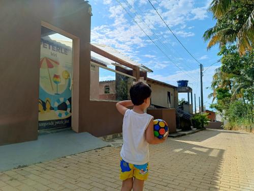 a young boy holding a ball in front of a house at Casa Temporada peterle Iriri in Iriri