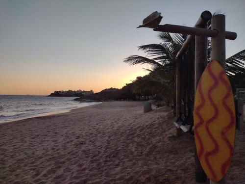 a surfboard hanging on a fence on a beach at Casa Temporada peterle Iriri in Iriri