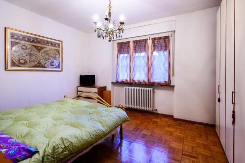 a bedroom with a bed and a window and a chandelier at Rètro Apartment In The Mountains in Mezzolombardo