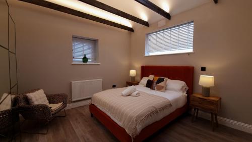 a bedroom with a bed and a chair and two windows at Sunshine 2 Bed Townhouse Brighton in Brighton & Hove
