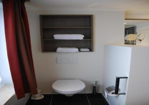 a bathroom with a white toilet and towels at Hotel Rubens in De Haan