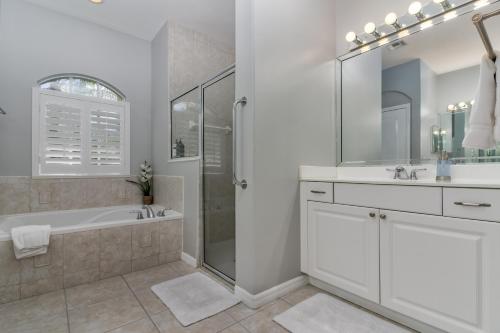 a white bathroom with a tub and a sink at Private Heated Pool & Beach House in Vero Beach