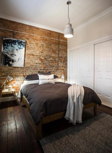 a bedroom with a brick wall and a large bed at The Cottage on Market in Mudgee