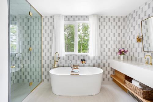 a white bathroom with a tub and a window at Manoir Hovey, Relais & Châteaux in North Hatley