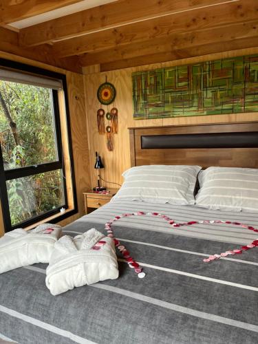 a bedroom with a large bed with red and white pillows at Aysén Lodge - Cabaña con Tinaja in Puerto Dunn