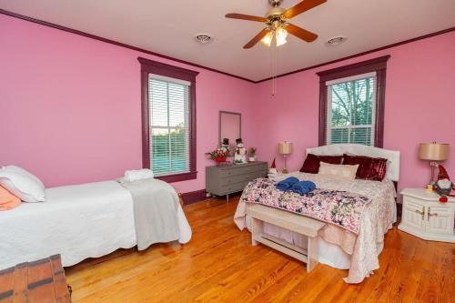 een roze slaapkamer met 2 bedden en een plafondventilator bij The Bagley House: built in 1911 in Blackstone