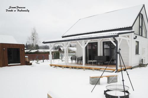a white house with a pavilion in the snow at SzumiPuszcza - domki, sauna, balia in Białowieża