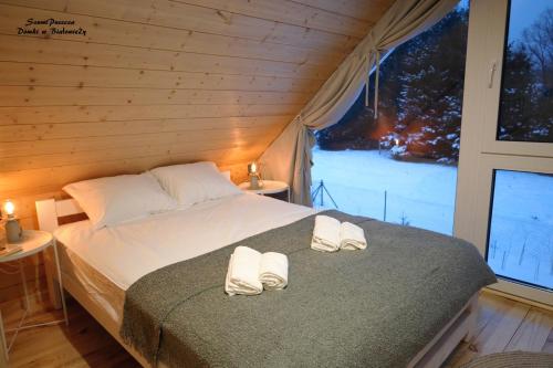 SzumiPuszcza - domki, sauna, jacuzzi في بياوفييجا: غرفة نوم عليها سرير وفوط