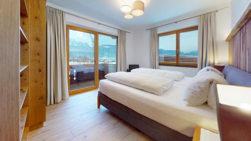 Schlafzimmer mit einem Bett mit weißen Kissen und Fenstern in der Unterkunft Apartments Aeon in Sankt Johann in Tirol