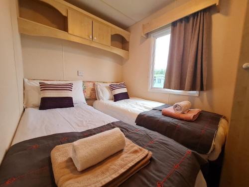 een kleine kamer met 2 bedden en een raam bij BLUE BIRD HOLIDAY HOME in Durham