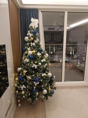 a christmas tree with blue and white decorations in a room at 33 floor, luxury apartment, amazing view Sky City Cevahir-Skopje in Skopje