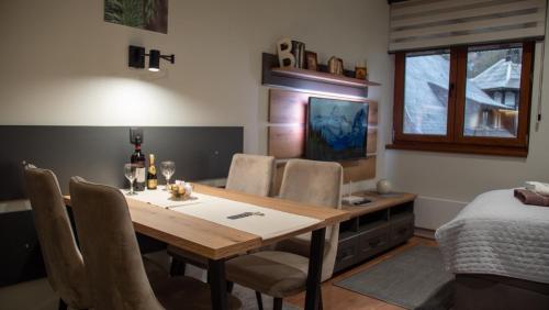 a dining room with a table and chairs and a bed at Regulus apartment Brzeće Kopaonik in Brzeće
