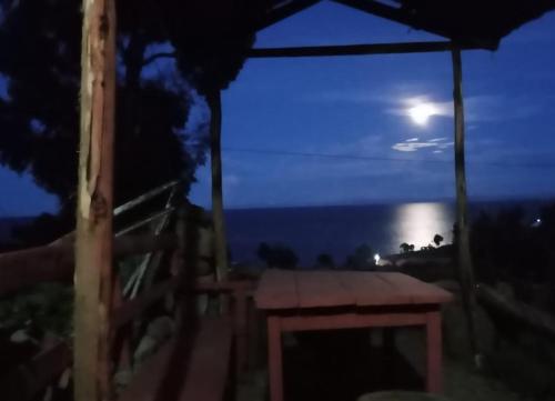 a picnic table under an umbrella at night with the moon at BLUE SKY Amantani Lodge in Ocosuyo