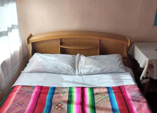a bed with a wooden headboard and a colorful blanket at BLUE SKY Amantani Lodge in Ocosuyo