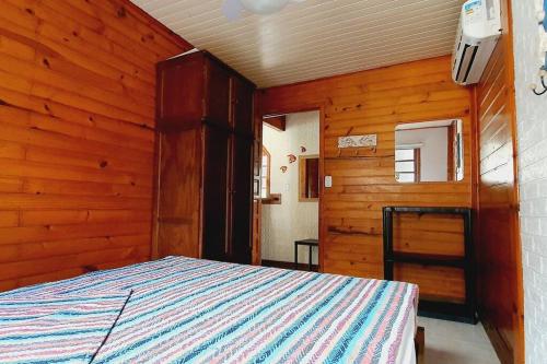 een slaapkamer met een bed in een kamer met houten wanden bij Chalé super aconchegante em condomínio com garagem in São Sebastião