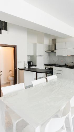 a white kitchen with a table and white chairs at AXARA Holiday Home in Xagħra
