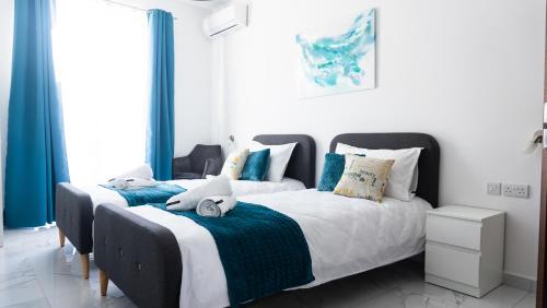 two beds in a bedroom with blue curtains at AXARA Holiday Home in Xagħra