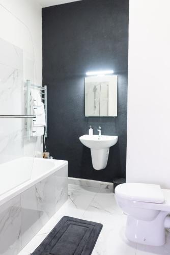 a black and white bathroom with a sink and a toilet at AXARA Holiday Home in Xagħra
