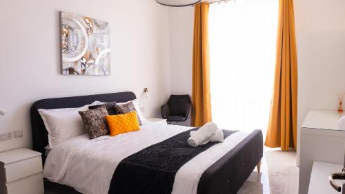 a bedroom with a large bed with orange curtains at AXARA Holiday Home in Xagħra