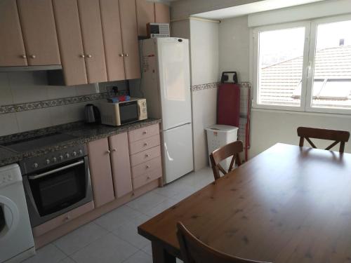 uma cozinha com uma mesa e um frigorífico branco em Cimadevilla Apartamento San Pedro em Gijón