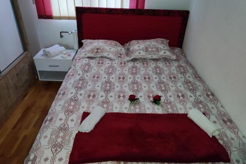 a bed with two roses on top of it at Vela-edo in Zavidovići